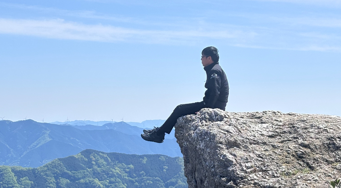 見晴らしのいい山の上で遠くを眺めるかずお君